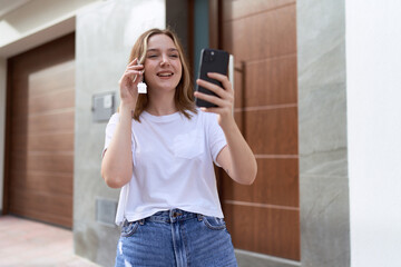 Wall Mural - Young caucasian woman having video call holding key of new home at street