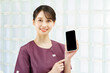 © maru54 - スマートフォンの画面を見せるユニフォーム姿の女性
