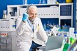 © Krakenimages.com - Middle age man with grey hair working at scientist laboratory doing video call screaming proud, celebrating victory and success very excited with raised arm
