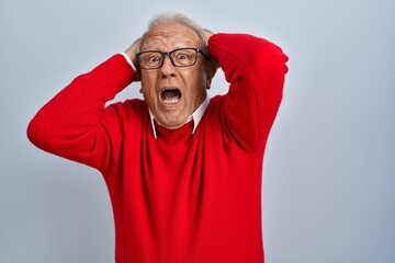 Sticker - Senior man with grey hair standing over isolated background crazy and scared with hands on head, afraid and surprised of shock with open mouth