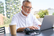 © insta_photos - Older senior business man using laptop elearning sitting outside. 60 years old adult professional businessman working online on computer, watching webinar, learning or having remote video call.