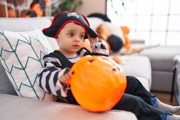 Sticker - Adorable hispanic boy having halloween party holding pumpkin basket at home