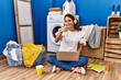 © Krakenimages.com - Young hispanic woman studying while waiting for laundry pointing fingers to camera with happy and funny face. good energy and vibes.