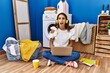 © Krakenimages.com - Young hispanic woman studying while waiting for laundry angry and mad screaming frustrated and furious, shouting with anger. rage and aggressive concept.