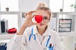 © Krakenimages.com - Young blonde woman doctor holding heart over eye at clinic