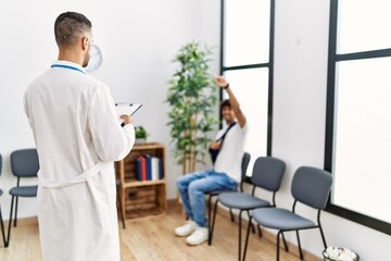 Wall Mural - Two hispanic men doctor and patient at hospital waiting room