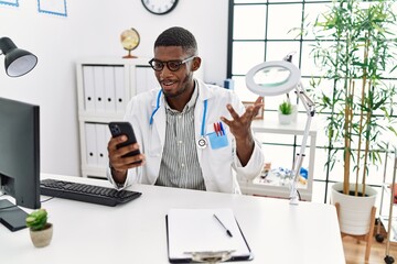 Sticker - Young african american man wearing doctor uniform having video call at clinic