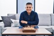 © Krakenimages.com - Young latin man playing chess sitting on sofa at home