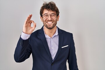 Poster - Hispanic business man wearing glasses smiling positive doing ok sign with hand and fingers. successful expression.