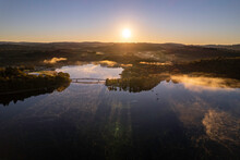 Aerial View Of Lac De Saint Pardoux And Its Footbridge At Sunrise In Autumn With Fog And Mirror Water