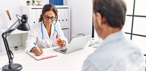 Canvas Print - Middle age man and woman wearing doctor uniform prescribe pills at clinic