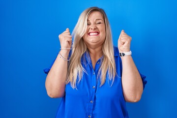 Sticker - Caucasian plus size woman standing over blue background excited for success with arms raised and eyes closed celebrating victory smiling. winner concept.