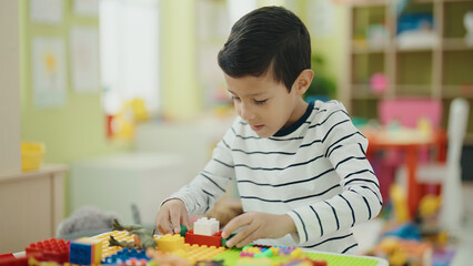 Canvas Print - Adorable hispanic boy playing with construction blocks sitting on table at kindergarten