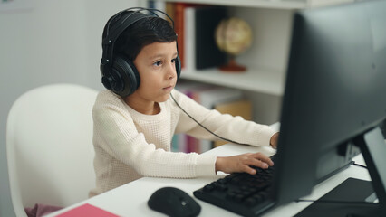 Canvas Print - Adorable hispanic boy student using computer sitting on table at classroom