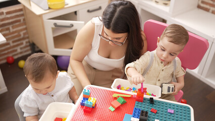 Poster - Teacher and preschool students playing with construction blocks and cars sitting on table at kindergarten