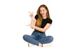 © Asier - Young redhead woman sitting on the floor cut out isolated pointing with forefingers to a copy space, expressing excitement and desire.