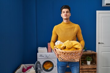 Canvas Print - Young hispanic man holding laundry basket looking at the camera blowing a kiss being lovely and sexy. love expression.