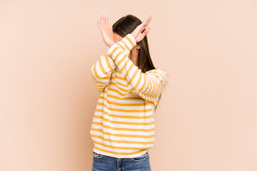 Young colombian woman isolated on beige background keeping two arms crossed, denial concept.