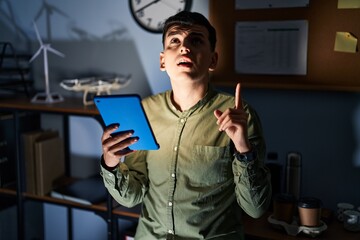 Canvas Print - Non binary person using touchpad device at night amazed and surprised looking up and pointing with fingers and raised arms.