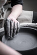Women working at pottery wheel, creating dishes. The dirty hands of the potter in the clay and on the wheel. Creation.