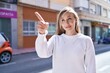 © Krakenimages.com - Young blonde woman smiling confident pointing with finger at street