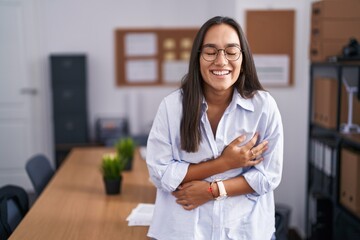 Wall Mural - Young hispanic woman at the office smiling and laughing hard out loud because funny crazy joke with hands on body.