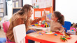 Leinwandbild Motiv Adorable hispanic girl playing with maths puzzle game high five with teacher at kindergarten