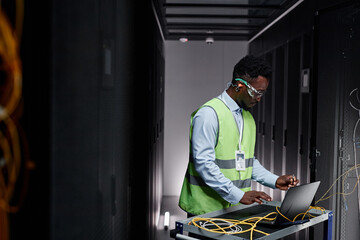Graphic side view portrait of young network technician repairing servers in data center, copy space