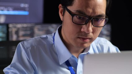 Close Up Of Asian Male Programmer Writing Code By A Laptop Using Multiple Monitors Showing Database On Terminal Window Desktops In The Office

