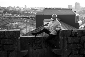 Sticker - A female tourist sits on a masonry wall in Porto, Portugal. Black and white photo.