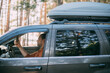 © Anna - A young man driving a car in a pine forest on the shore of a lake on a sunny day. Traveling by car.