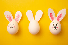Food Photo For Happy Easter. Chicken Egg With Cute Rabbit Faces And Bunny Ears On Yellow Background. White Empty Egg For Coloring For Children. Banner. Greeting Card For Celebration. Copyspace. Gift