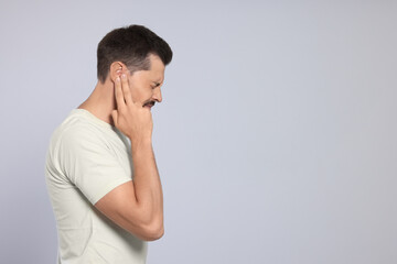 Wall Mural - Man suffering from ear pain on grey background, space for text