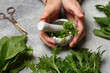 © New Africa - Woman grinding fresh green herbs in mortar at light grey table, closeup
