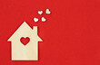 © sav_an_dreas - Wooden house with decorative hearts on a red background, flat lay, space for text.