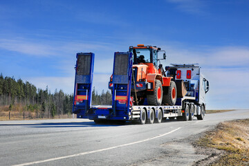 Wall Mural - White Semi Truck Transports Wheel Loader, Rear View. Copy Space. 