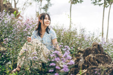 Asian Travel Woman Relax Sitting In Wild Flower Field In Morning Mood On Spring Or Summer