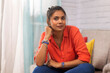 © IndiaPix - Portrait of a young woman looking at camera while sitting on sofa in living room