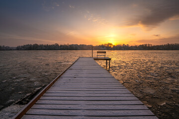 Wall Mural - frosted pier over a frozen river during a beautiful sunrise