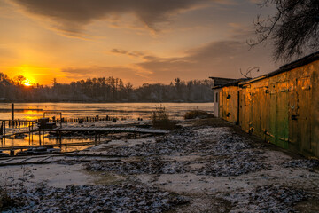 Wall Mural - fishing boat garages in a marina on a frozen river during a beautiful sunrise