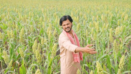 Wall Mural - Happy smiling young farmer showing grown crop by felling at farmland - concept of freedom, positive emotion and agriculture.