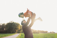 Man Lifting Son Wearing Flying Goggles In Autumn