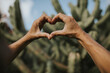 © Westend61 - Hands of woman gesturing heart shaped in front of cactus plants