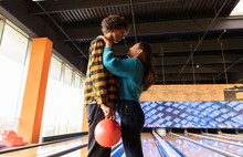 Young Couple With Bowling Ball Standing Together At Alley