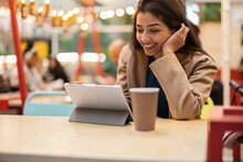 Happy Young Woman Using Tablet Computer In Cafe