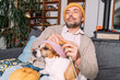 © Westend61 - Man with dog knitting on couch at home