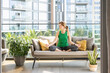 © Westend61 - Woman in lotus position sitting on sofa on balcony