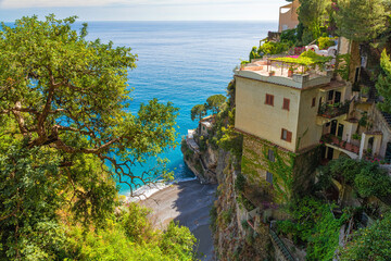 Wall Mural - Beautiful view of Italian villa on Amalfi coast on the cliff above Mediterranean sea with small beach. Summer resort