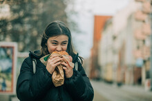 Teenage Girl Eating Burger On Street