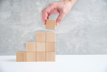 Laying out by hand steps of wooden cubes leading top.Concept growth and development business.